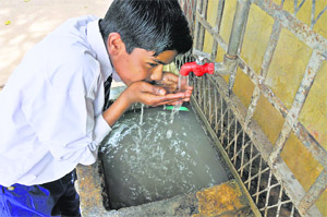 A student drinks water from an unpurified tank at Government High School, Satwari, Jammu. 