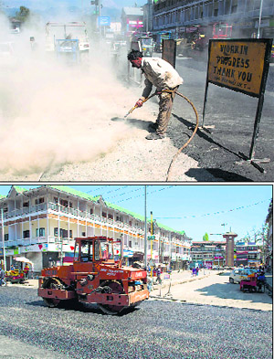 A worker cleans a road before repairing it at Lal Chowk; and (below) a road being coated with tar in Srinagar.