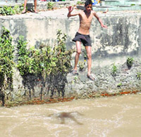 A boy jumps into the Ranbir Canal to beat the heat in Jammu on Sunday. 