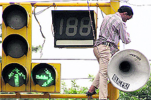 A worker fixes a loud speaker atop the traffic lights at a chowk in Jalandhar