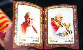 A Polish pilgrim displays a souvenir of canonised Popes John Paul II (L) and John XXIII at the Vaticans St Peters Square.