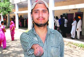 A youth who lost both his hands due to an electric shock shows the ink mark on his arm after casting vote in Dera Bassi on Wednesday.