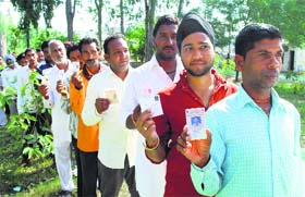 Making it count: Women and men wait for their turn to vote at Badal village in Majitha in Amritsar district