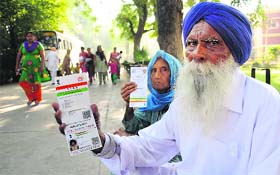 Dhanna Singh (88) and Maniyari Kaur (76) show their Aadhaar cards outside a polling booth in Ludhiana on Wednesday