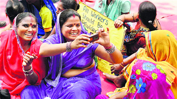 Members of Indian Federation of Trade Unions Delhi Committee take photographs using a moble phone at a protest demanding better wages and working conditions, on May Day in New Delhi on Thursday