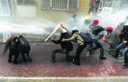 Protesters shield themselves as the riot police use water cannon to disperse them during a May Day protest in Istanbul.