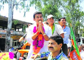 Actor Amisha Patel waves at a crowd during a roadshow of the Congress in Mandi on Friday