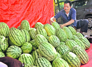 A roadside vendor sells watermelons during a hot day in Jammu on Friday.