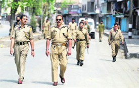 Police officers patrol Srinagar during curfew on Friday
