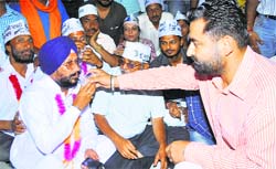 Jaskiran Teja, Patiala SP, offers water to an AAP leader on fast in Patiala on Friday. Tribune photo