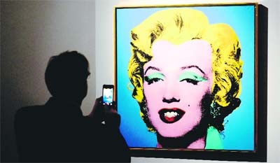 A man takes a picture of Blue Shot Marilyn, a painting by US artist Andy Warhol, as part of the exhibition Warhol in Rome.