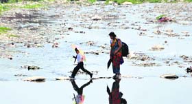 A child walks through a flooded area to go to school with his mother in Dehradun on Monday.
