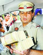 Police official displays money seized from liquor shops in Amritsar.