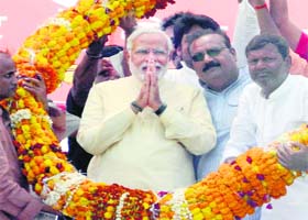 BJP prime ministerial candidate Narendra Modi is garlanded during an election campaign rally in Mahrajganj on Tuesday