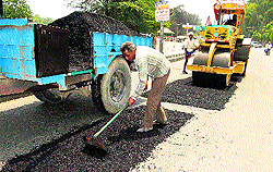 Workers fill potholes near Rose Garden in Bathinda on Wednesday