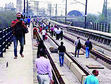 Delhi Metro commuters walk on the track at Yamuna Bridge in New Delhi on Wednesday