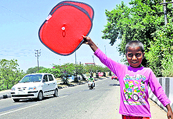 A boy sells sunshades for vehicles at a roadside in Jammu