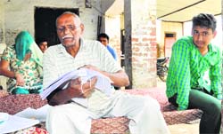 Hari Kishan shows the documents in connection with his land case at his residence in Kharbala village near Hansi in Hisar district. Tribune photo: Parvesh Chauhan