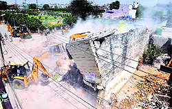 A JCB machine demolishes a structure at Gyaspura in Ludhiana on Thursday