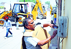an MC worker disconnects an illegal electricity connection