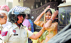 A policewoman pacifies a woman, whose house was demolished by MC workers