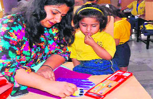 A woman makes a greeting card as her daughter looks on during the Mother's Day celebrations held at Sanskriti School in Haridwar on Friday.