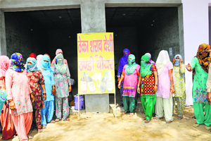 Women stand in front of a liquor vend at Kinana village after locking it. 