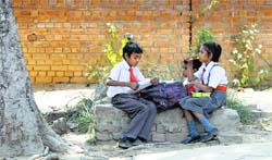 Schoolchildren sit under the shade of a tree on a hot and humid Friday. Tribune photo: Himanshu Mahajan