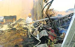 A firefighter douses the flames at the factory in Khanna. A tribune photograph