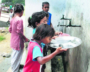 A student quenches her thirst by using a plate to drink water at a government school in Jalandhar.