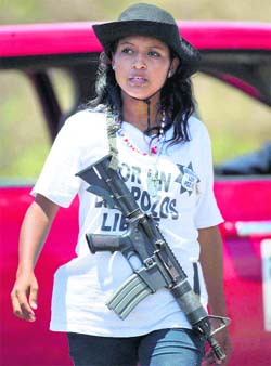An armed female member of the Self-Defense Council of Michoacan patrols a checkpoint set up by the self-defence group in Chuquiapan in Mexico.