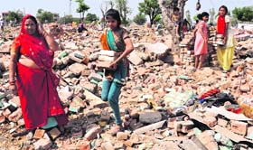 Residents collect bricks from the debris of their demolished houses at Nehru Colony in Sector 53, Chandigarh, on Sunday.