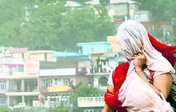 A girl shields herself during a storm in Mandi on Sunday