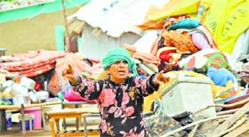 A woman protests near the household items piled up outside her hutment in Jammu on Sunday.