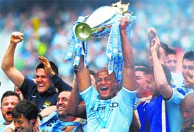 Manchester Citys captain Vincent Kompany (centre) celebrates with the English Premier League trophy following their win over West Ham United in Manchester on Sunday