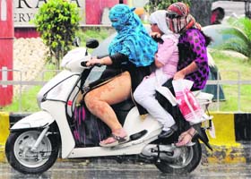Cool showers: Three girls ride a scooter in the rain in Amritsar on Monday