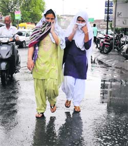 Two girls walk amidst rain in Bathinda on Monday.