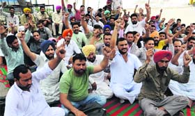 Contractual PRTC workers stage a protest outside the main workshop in Bathinda on Monday.