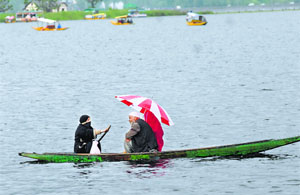 A Kashmiri couple with their daughter ride a shikara on the Dal Lake during rain in Srinagar on Tuesday.