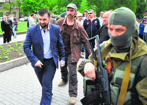An armed pro-Russia militant escorts Denis Pushilin (L), the self-styled governor of the so-called People's Republic of Donetsk, as he walks near the regional state building seized by separatists in the eastern Ukrainian city of Donetsk on Tuesday.