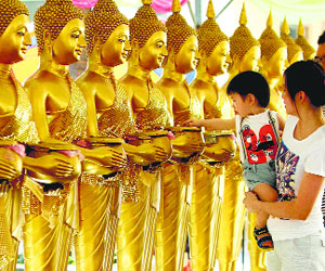 A boy drops coins into Buddha statues as a symbol of blessings on Wesak Day at the Thai Buddhist Chetawan Temple in Petaling Jaya, near Kuala Lumpur, on Tuesday.