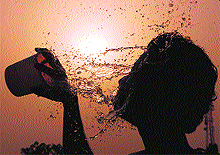 A boy washes his face with water do get relief from the hot weather in Dehradun on Wednesday