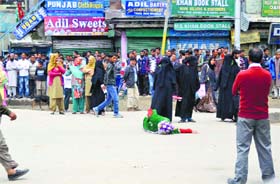 A woman lies down on the road in protest against her sons arrest in Baramulla district