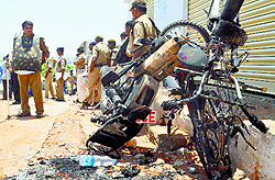 Policemen collect evidence near a charred motorcycle in the Kishanbagh area of Hyderabad on Wednesday after communal clashes broke out over alleged burning of a religious flag