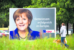 A woman walks past a poster of German Chancellor and Christian Democratic Union head Angela Merkel for the European elections in Berlin on Wednesday