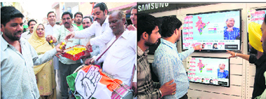 people watch election results at a shop; and workers celebrate the victory of the Congress in Amritsar on Friday.