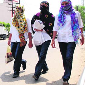 Too much in the sun: Girls cover their faces on a hot summer afternoon in Amritsar on Saturday