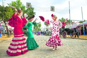 Women wearing traditional Andalusian dresses dance at the Sevilla Fair