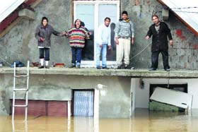 People stand on a terrace of their flooded house as the wait to be evacuated in the town of Obrenovac, southwest of Belgrade