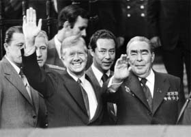US President Jimmy Carter (L) and USSR State and party chairman Leonid Brezhnev (R) wave, as the Soviet interpreter Viktor Sukhodrev (C) stands between them in Vienna